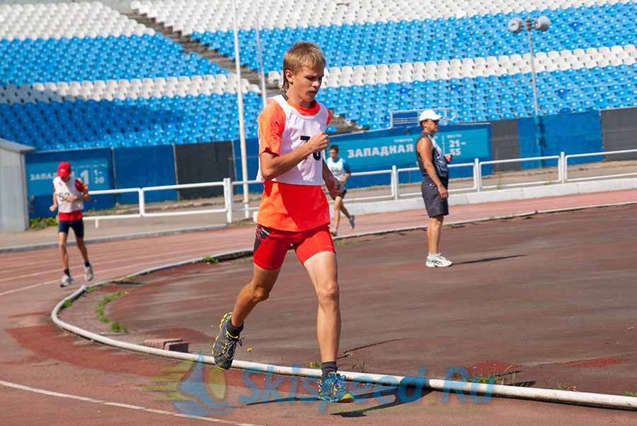 Спортсмен бежит на стадионе. Контрольная тренировка лыжников на Шиннике