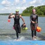 Мужчина и женщина в гидриках выходят из воды. Заплыв на открытой воде Iver Swim