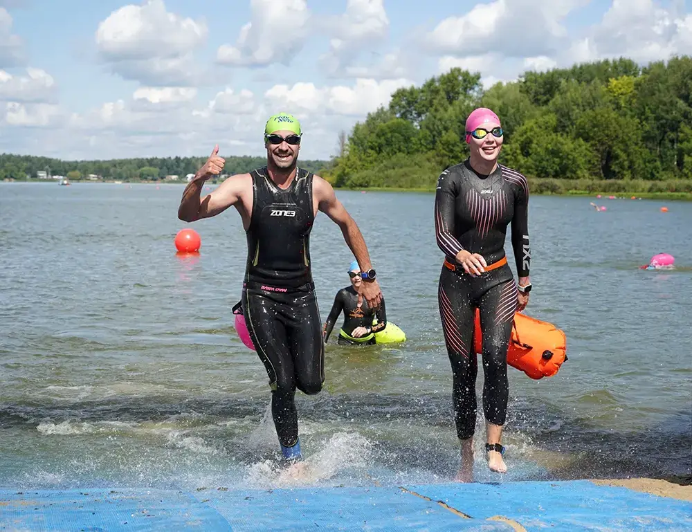 Мужчина и женщина в гидриках выходят из воды. Заплыв на открытой воде Iver Swim